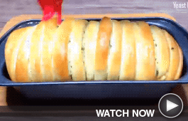 a chef brushes garlic butter on bread