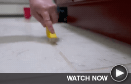 Close up of someone cleaning grout on kitchen tiles.