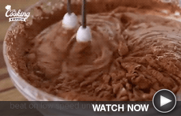 A hand mixer mixes chocolate batter